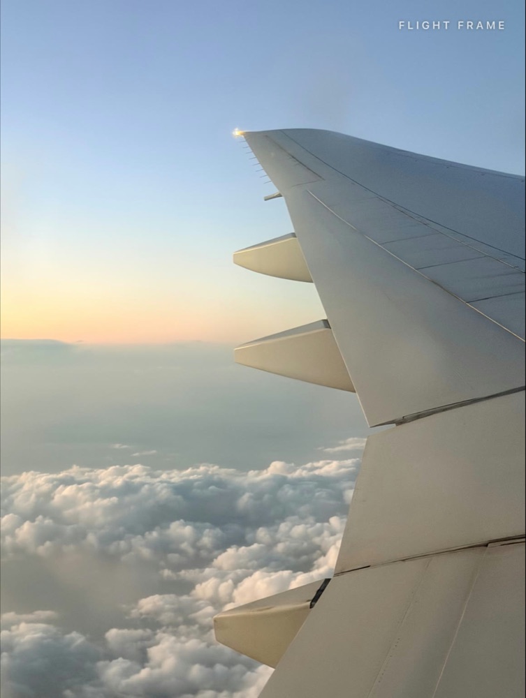 Boeing 777 wing above the clouds at sunrise